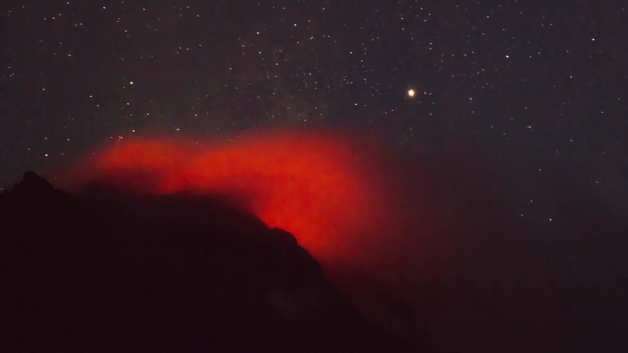 Active volcano smoking during the starry night