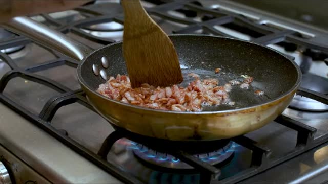 Frying diced bacon in a skillet