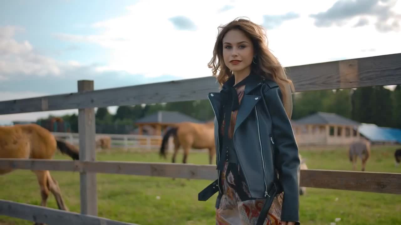 Woman walking near enclosure with horses