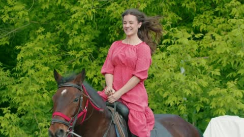 Young woman with braces in pink dress riding a horse