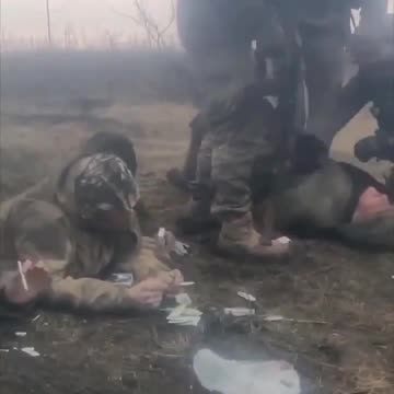 Russian POWs, two are smoking, the third with hands tied is being beaten up by Ukrainian soldiers