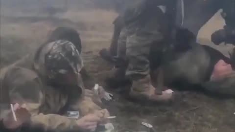 Russian POWs, two are smoking, the third with hands tied is being beaten up by Ukrainian soldiers