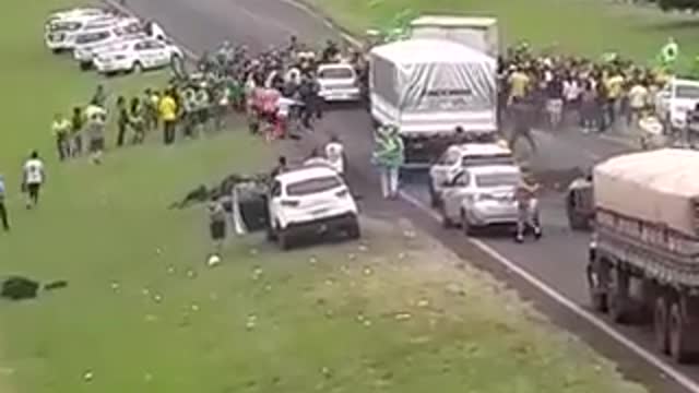 Someone drives through and over Bolsanoro supporters gathered in the road.