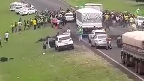 Someone drives through and over Bolsanoro supporters gathered in the road.