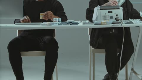 Man using a computer and a woman counting money!