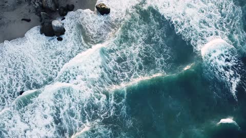 Drone view of large waves rushing towards the shore