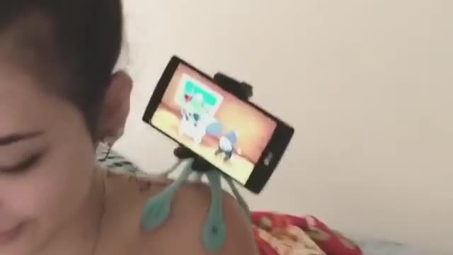 The mother feeds the baby while letting the baby watch the video