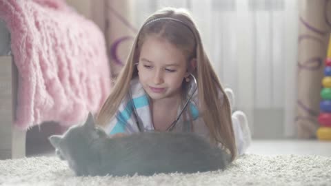 Child girl playing doctor with cat at home. Girl playing veterinarian with home pet