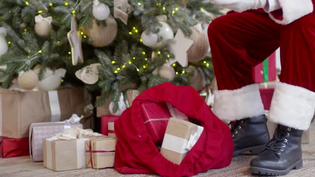 santa claus arranging gift boxes under the christmas tree