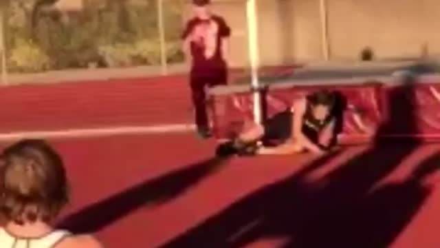 Track runner jumps backwards over bar and misses, fall off safety pad onto ground