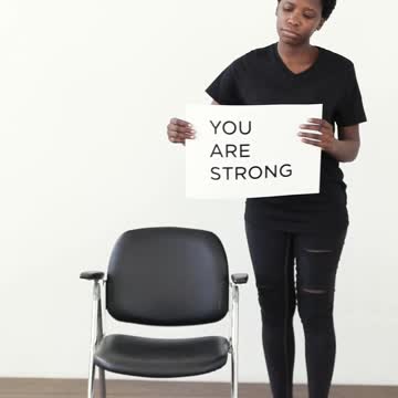 A Woman Picking Up a Placard on an Armchair