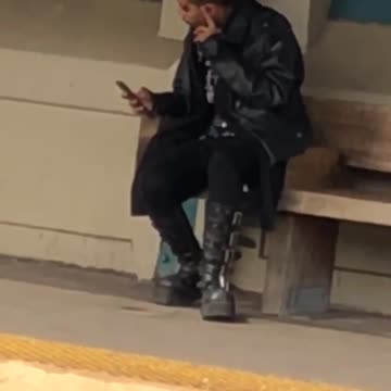 Guy with boots with mohawk waiting for train at train station