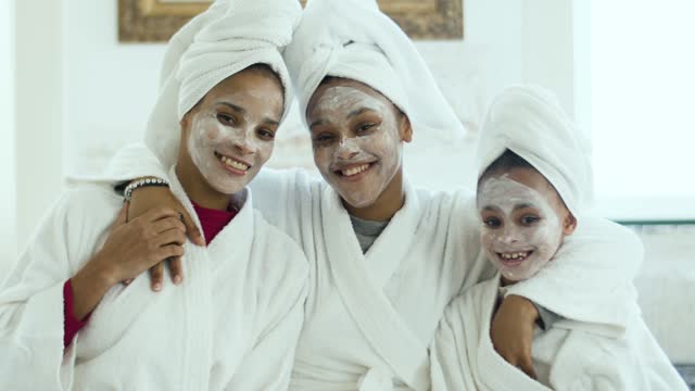 Mother and daughters in their bathrobes with face cream