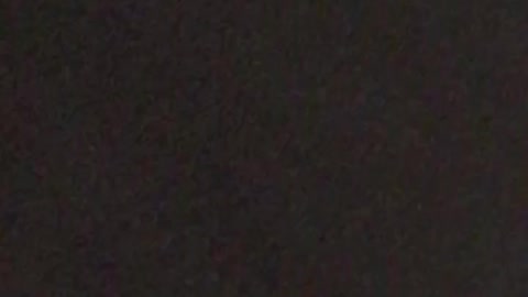 Guy takes a ball and breaks a window on a black car at night