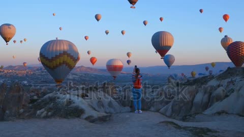 Backpack looks to the air balloon. Athletic girl and lots of hot air balloons