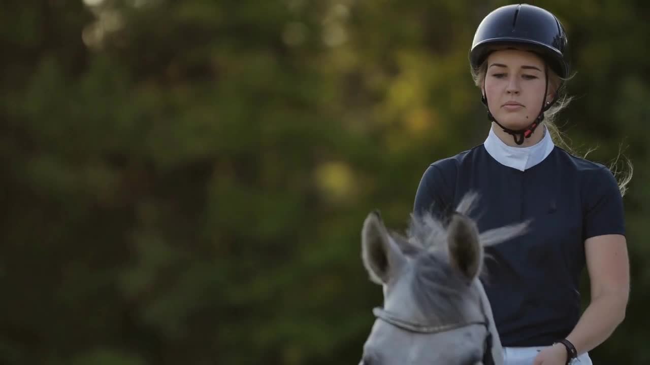 A female jockey is riding a horse. A female jockey is riding a horse in a corral