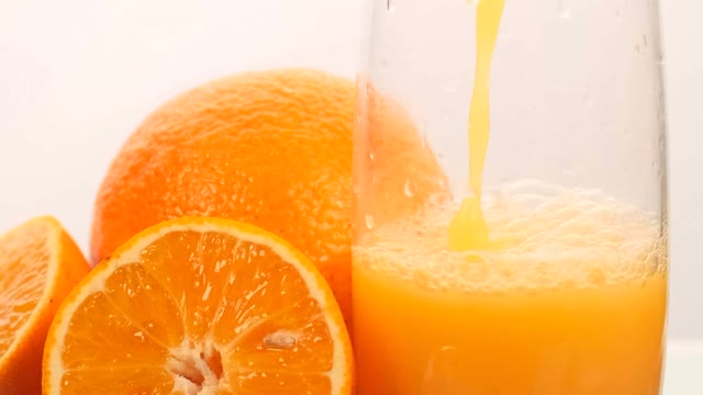 Serving juice in a glass with some oranges on a white background