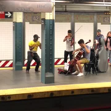 Guy yellow shirt dancing to violin duo subway