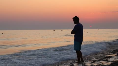 Meditative man on the shore of a beach at sunset