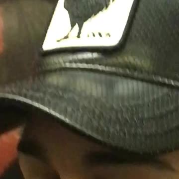 Zooming in a mans hat that says cock