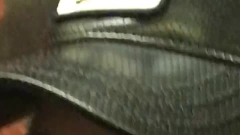 Zooming in a mans hat that says cock