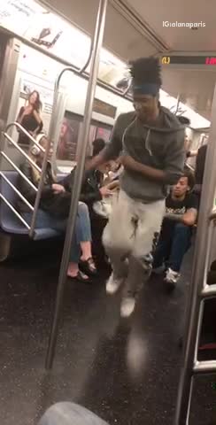 Two guys do spins and tricks on subway poles inside train
