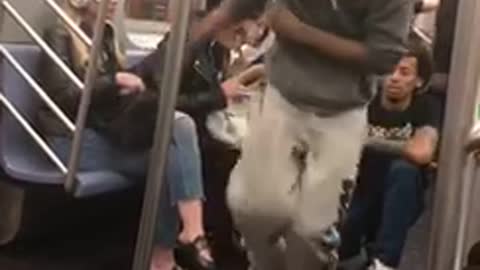 Two guys do spins and tricks on subway poles inside train