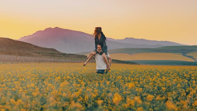 A Man is making fun of a woman on the shoulder in a flower field