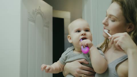 mother with her baby brushing her teeth and her son imitating her