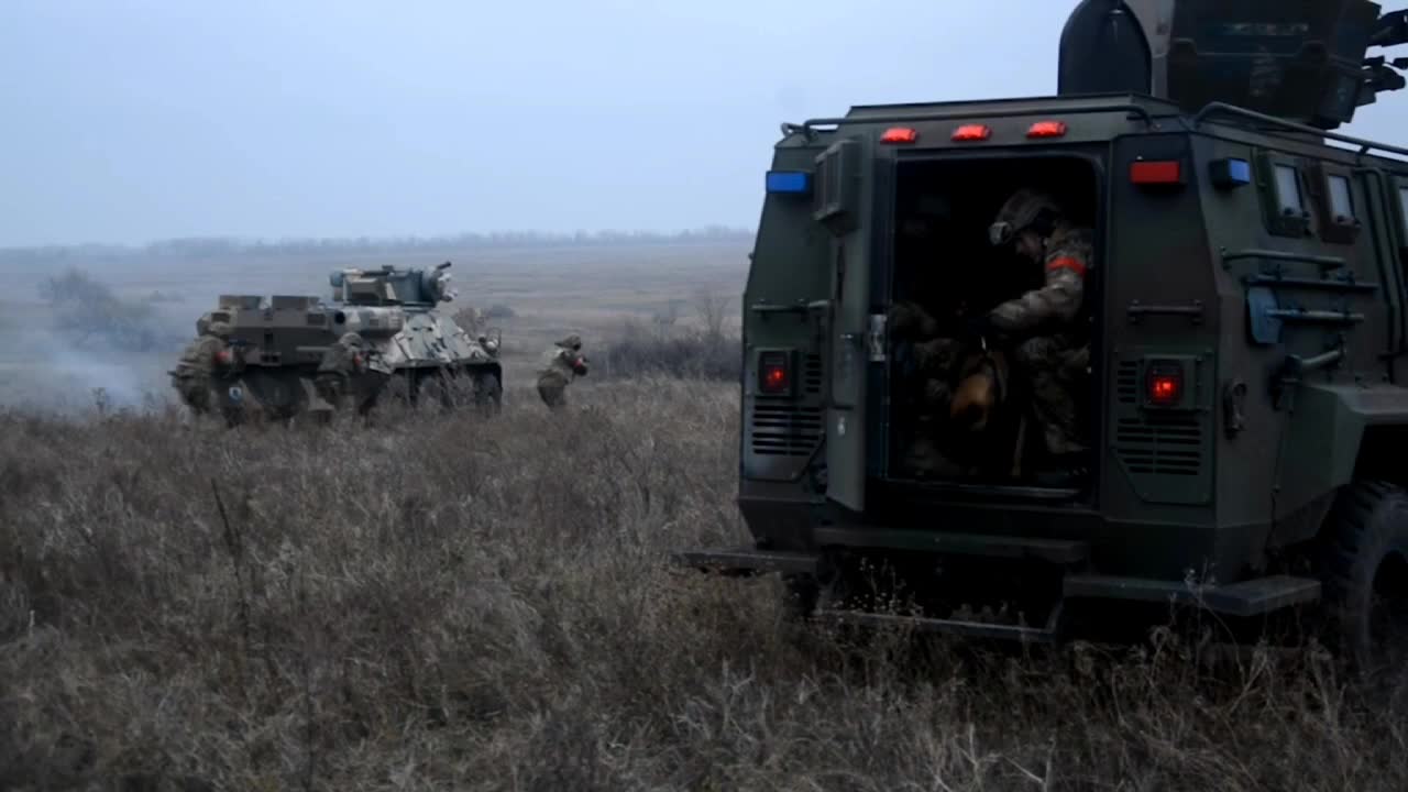 While shooting propoganda, the voice of the director is heard and the soldiers react to the command