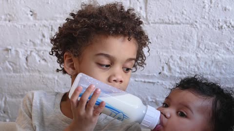 boy-holding-his-younger-brothers-milk-