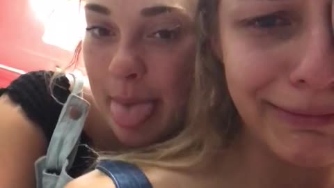 Girl in blue crying and friend holding her