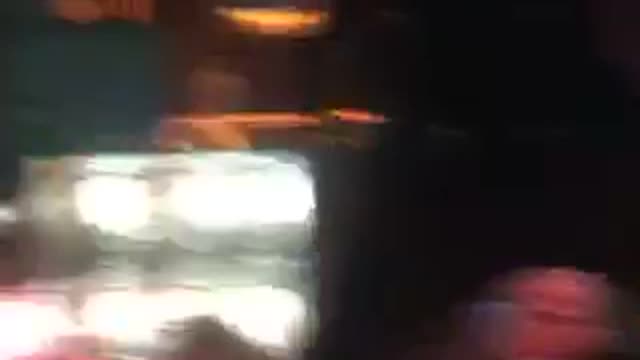 Guy pats bar stools while looking at people dancing on bar top