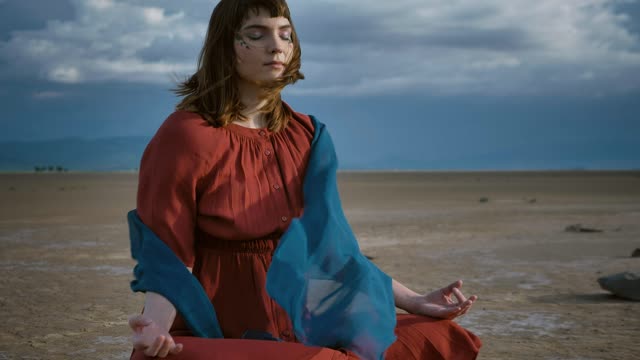 lady meditating under the breeze in the desert