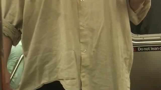 Person long white shirt singing hot in here subway holding cup