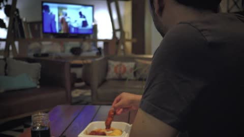 Young man eating while watching television