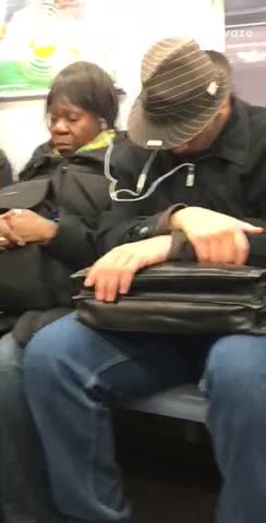 Man and woman share ear phones on subway train
