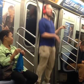 Guy blue shirt glasses red headphones dancing subway train
