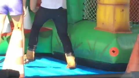 Guy in white shirt goes inside green inflatable castle