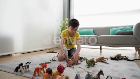 Boy sitting on carpet at home, play fighting with animal figurines