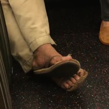 Zooming in on a mans toe nails on subway train