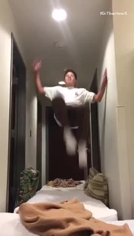 Kid in white shirt in hallway attempts backflip and fails