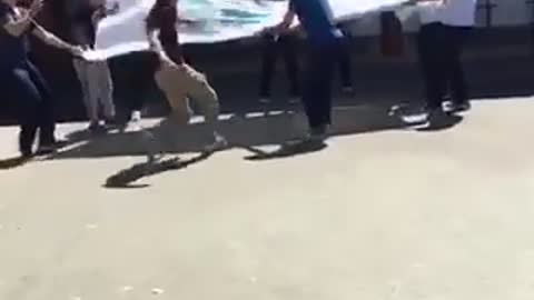 Kid jumps into sheet held by other kids
