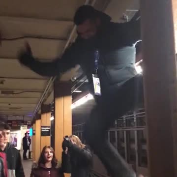 Man climbs and hangs on the side of pillar in subway train