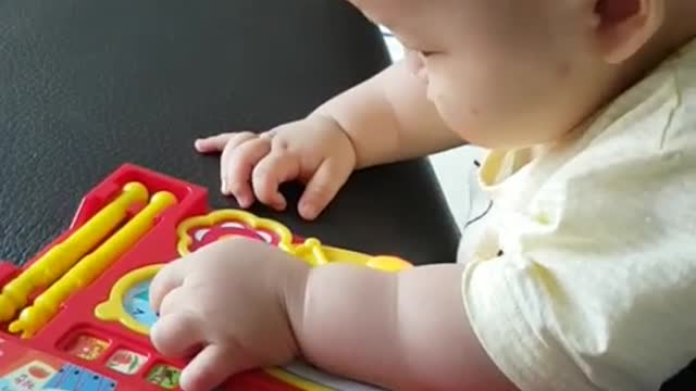 This is a video of a baby playing happily with a sound book.