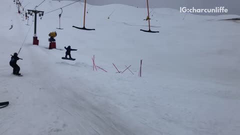 One person on snow board takes down another person in black outfit