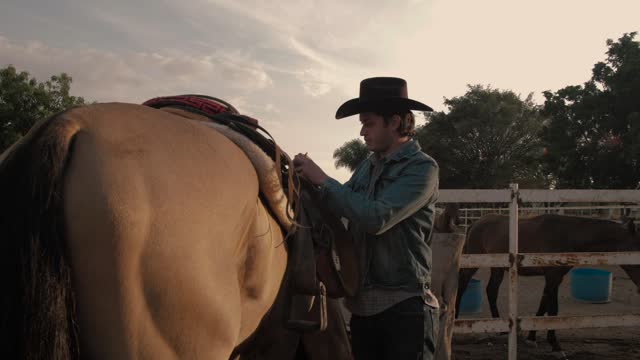 Rancher man tying a saddle chair to a horse