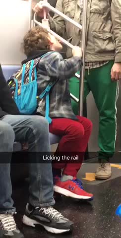 Boy in red pants licking rail on subway