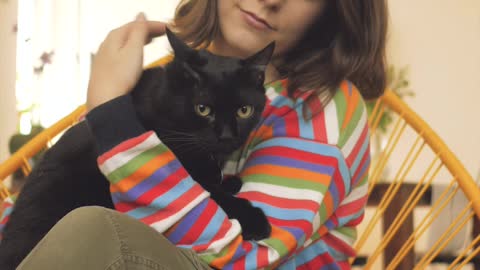 A woman petting a black cat