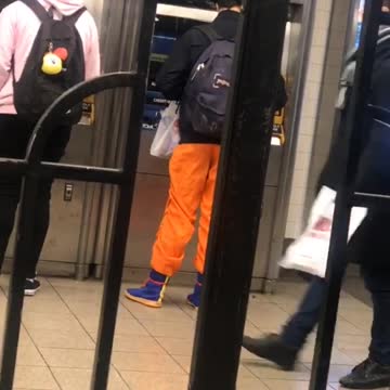 Guy wears orange ninja pants at subway station ticket booth